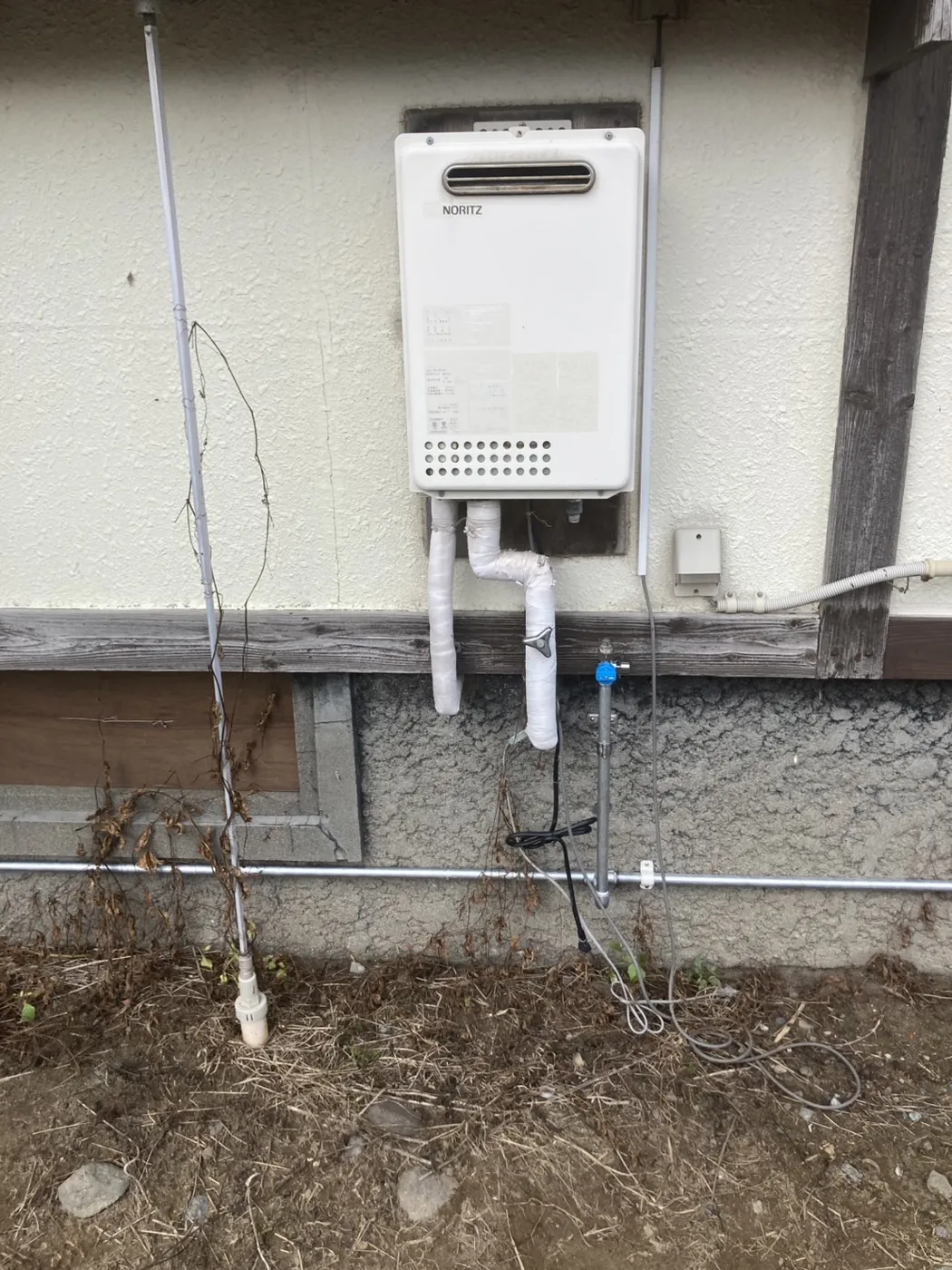 鶴岡市 交換前の経年したガス給湯器（配管の保温材がむき出しの状態）